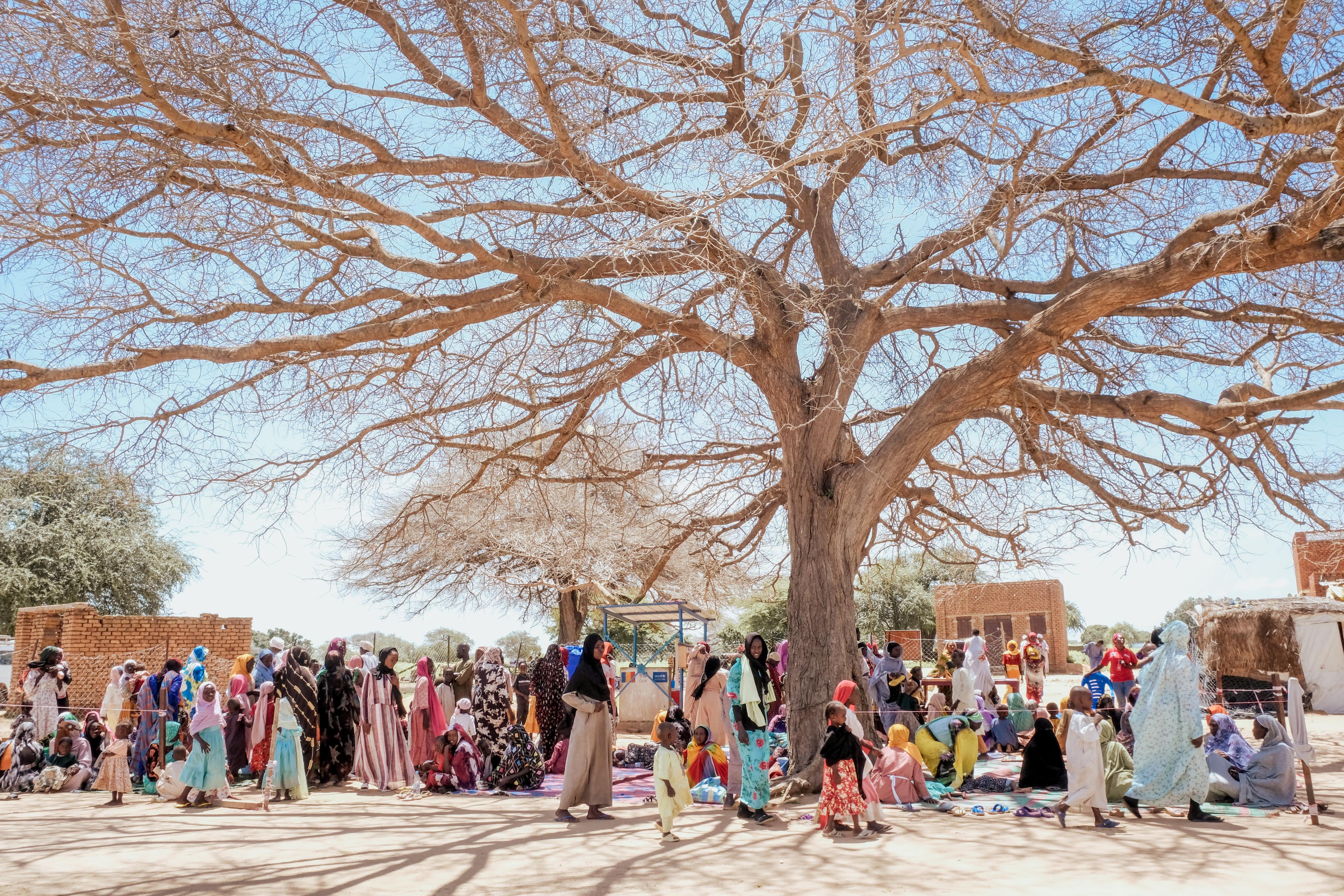 Les gens se rassemblent sous un arbre devant le centre de santé Première Urgence pour recevoir une vaccination contre le choléra.